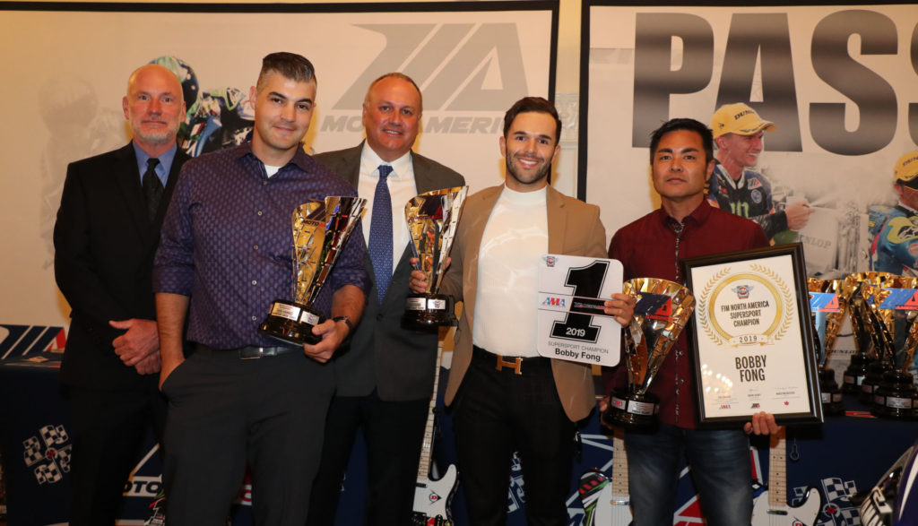 (From left to right) Massey, team manager Chris Ulrich, MotoAmerica Partner Chuck Aksland, Bobby Fong and crew chief Frank Aragaki help Fong with his Supersport Championship hardware. Photo by Brian J. Nelson.