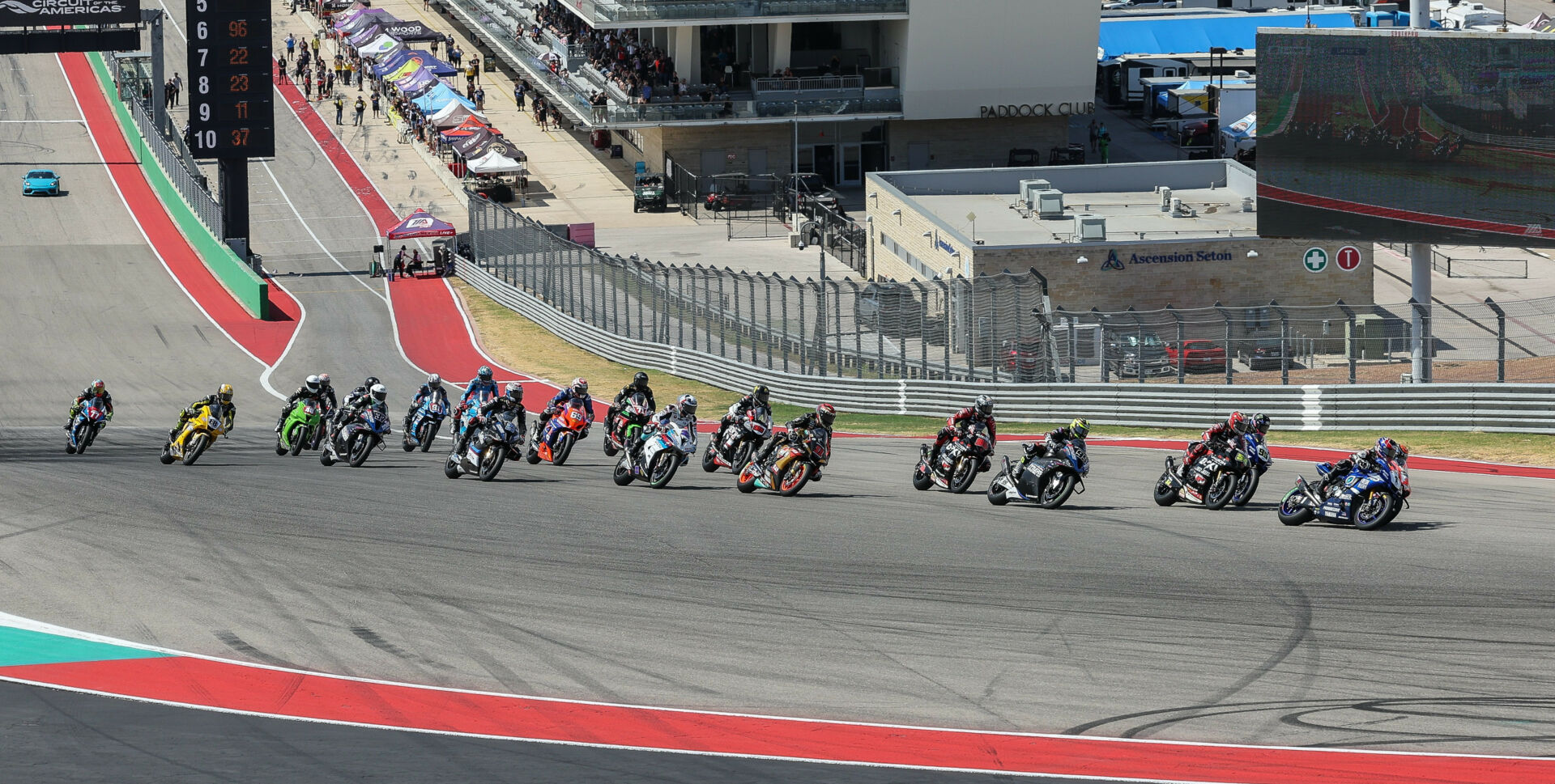 The start of MotoAmerica Superbike Race One at COTA with Jake Gagne (1) and Josh Herrin (2) fighting for the lead into Turn One ahead of Richie Escalante (54), JD Beach (95), PJ Jacobsen (99), Brandon Paasch (96), Mathew Scholtz (11), and the rest. Photo by Brian J. Nelson.