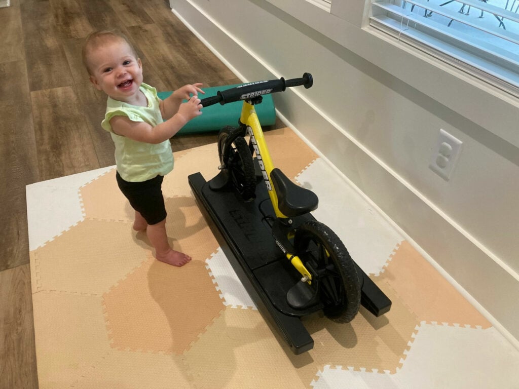 Olivia Grace "OG" Barnes, age 10 months, uses her Strider balance bike to stand and maintain her balance. Photo by Anne Barnes.