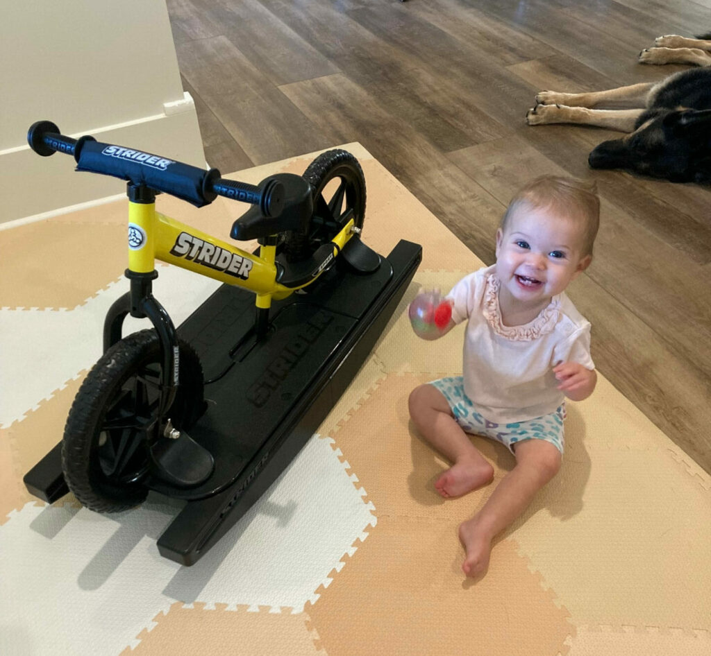 Olivia Grace "OG" Barnes, age 10 months, and her Strider balance bike on its rocker base. Photo by Anne Barnes.